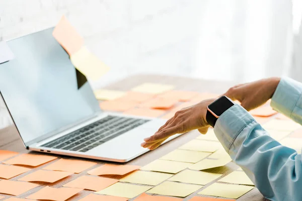 Selective focus of woman gesturing near laptop with blank screen and sticky notes — Stock Photo