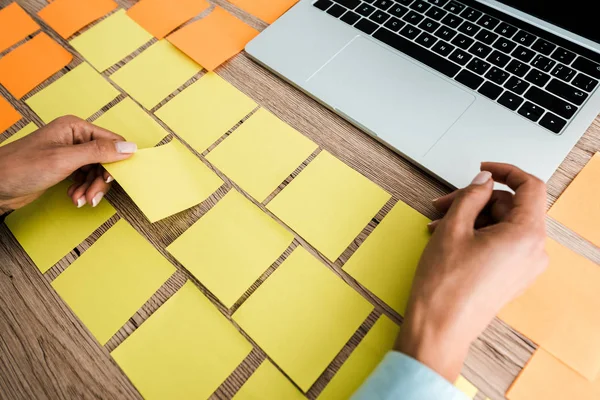 Cropped view of woman touching sticky note near laptop on desk — Stock Photo