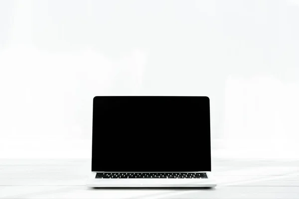 Modern laptop with blank screen on wooden surface on white — Stock Photo
