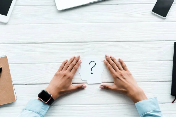 Ansicht von oben: Frau berührt Papier mit Fragezeichen in der Nähe von Gadgets auf dem Tisch — Stockfoto