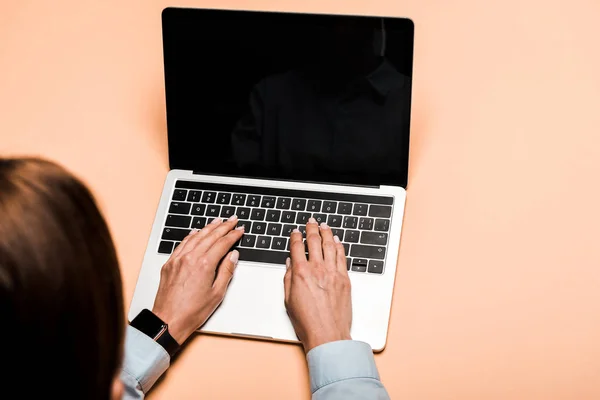 Cropped view of woman typing on laptop with blank screen on pink — Stock Photo