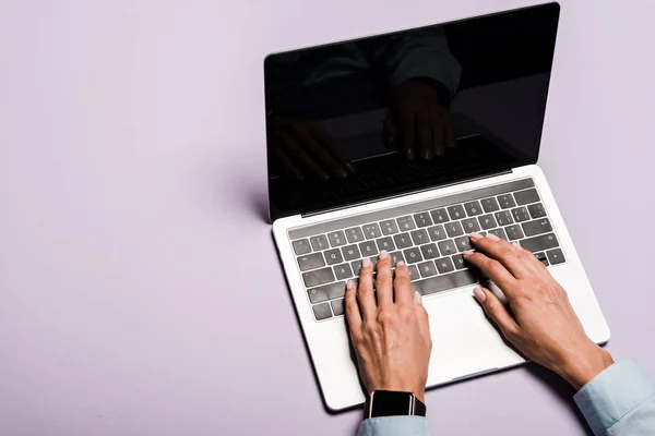 Cropped view of woman typing on laptop with blank screen on purple — Stock Photo