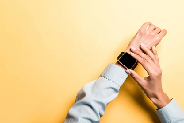 Abgeschnittene Ansicht einer Frau, die Smart Watch mit leerem Bildschirm auf Orange berührt — Stockfoto