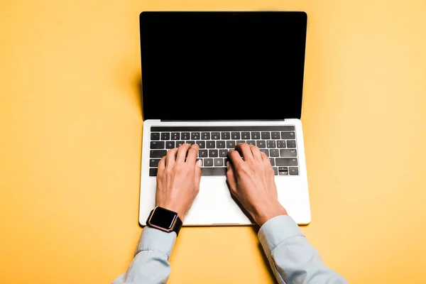 Vista recortada de la mujer escribiendo en el ordenador portátil moderno con pantalla en blanco en naranja - foto de stock