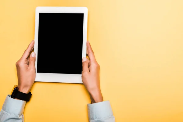 Vista recortada de niña sosteniendo tableta digital con pantalla en blanco en naranja - foto de stock