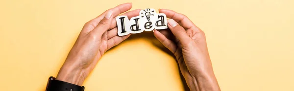 Panoramic shot of girl holding card with idea lettering on orange — Stock Photo