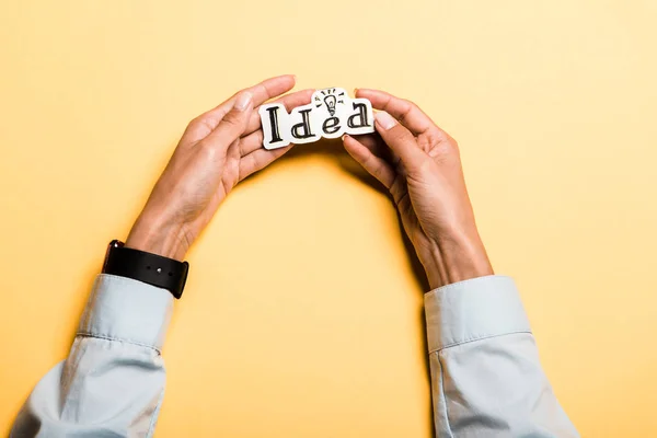 Top view of girl holding card with idea lettering on orange — Stock Photo