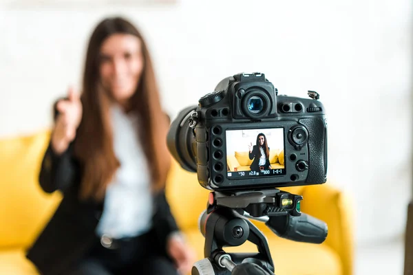 Selective focus of digital camera with happy video blogger showing thumb up on screen — Stock Photo