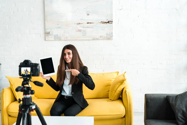 Foco seletivo do blogueiro de vídeo feliz apontando com o dedo para o tablet digital com tela em branco perto da câmera digital — Fotografia de Stock