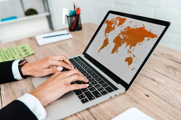 Foco seletivo de empresária digitando no laptop com mapa na tela — Fotografia de Stock