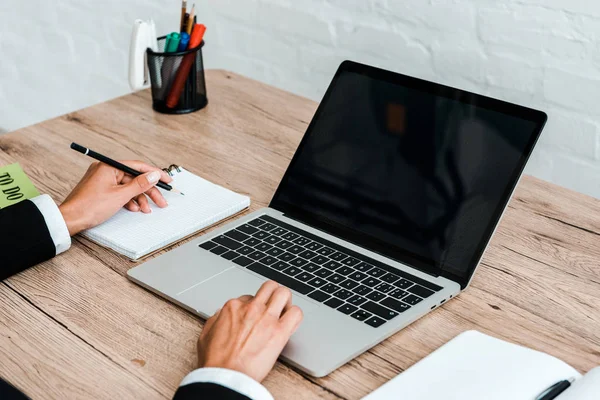 Vista cortada da mulher segurando caneta ao usar laptop com tela em branco — Fotografia de Stock