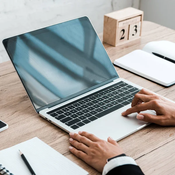 Foco seletivo da mulher usando laptop com tela em branco perto de notebooks e cubos de madeira com data e mês — Fotografia de Stock