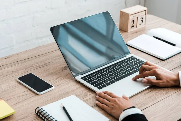 Vista recortada de la mujer cerca de gadgets con pantallas en blanco y cuadernos - foto de stock