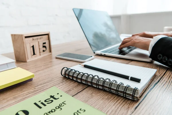 Selektiver Fokus der Frau beim Tippen auf Laptop neben Notizbuch und Holzwürfel — Stockfoto