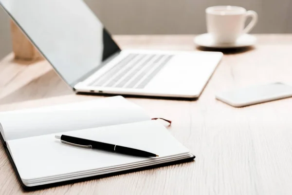 Foco seletivo de notebook com caneta perto de gadgets na mesa — Fotografia de Stock