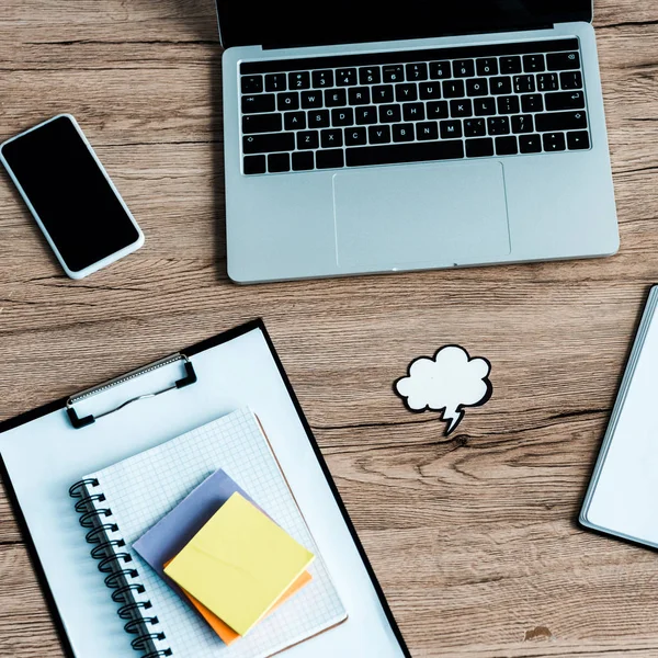 Top view of laptop near smartphone with blank screen and paper cloud and thunder — Stock Photo