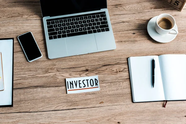 Top view of paper with investor lettering near gadgets on table — Stock Photo