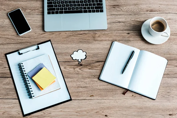 Vista superior de la computadora portátil cerca del teléfono inteligente con pantalla en blanco y notas adhesivas en el escritorio — Stock Photo