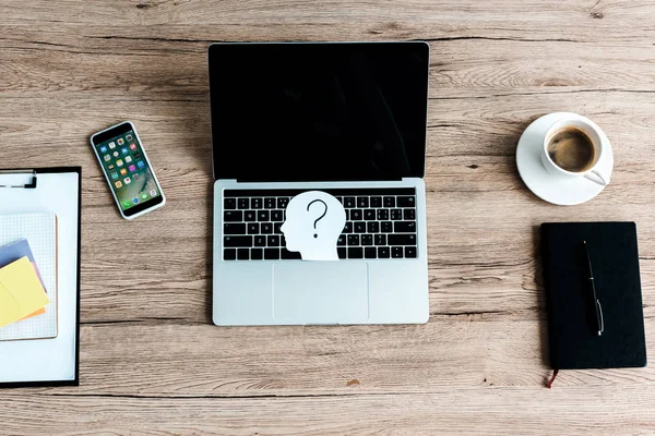 KYIV, UKRAINE - JULY 23, 2019: top view of iphone near laptop with blank screen and paper human head with question mark — Stock Photo