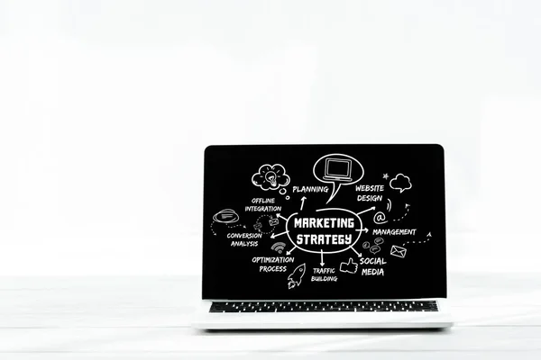 Portátil con letras de estrategia de marketing en pantalla en blanco - foto de stock