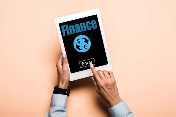 Cropped view of woman pointing with finger at digital tablet with finance lettering on pink — Stock Photo