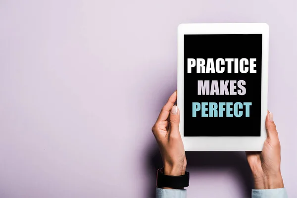 Cropped view of woman holding digital tablet with practice makes perfect lettering on purple — Stock Photo