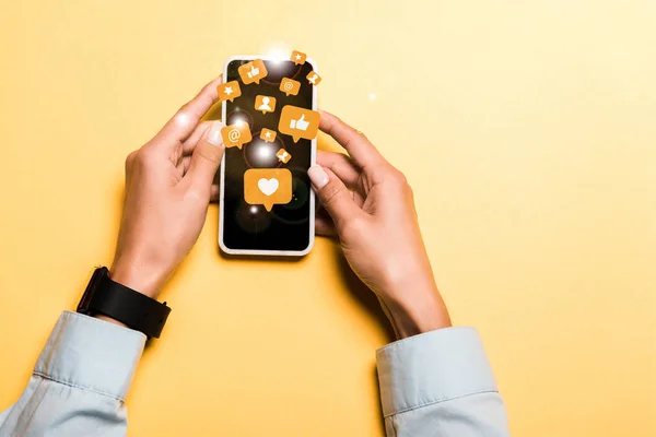 Cropped view of woman holding smartphone with speech bubbles with signs on orange — Stock Photo