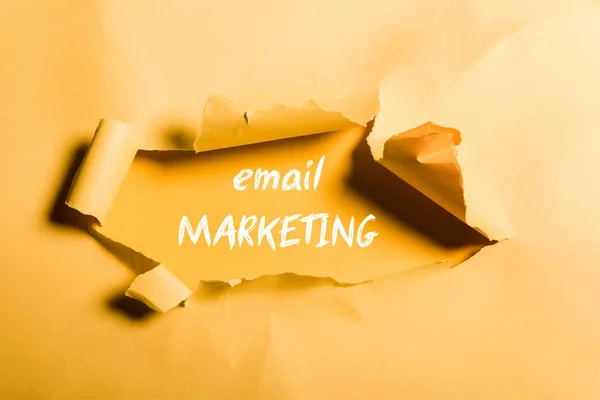 Carta frantumata con lettering e-mail marketing e bordi arrotolati su arancione — Foto stock