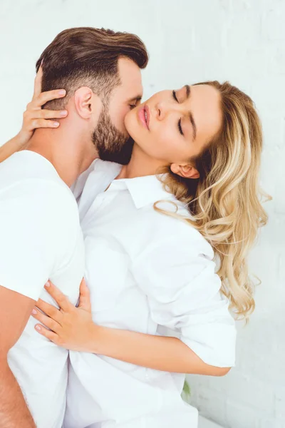 Young man hugging and kissing girlfriend dressed in white shirt — Stock Photo