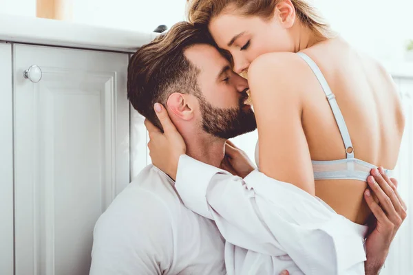 Jovem abraçando namorada bonita enquanto sentado no chão na cozinha — Fotografia de Stock