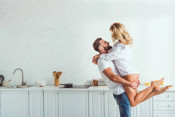 Handsome young man in blue jeans holding on hands beautiful girlfriend dressed in white shirt — Stock Photo