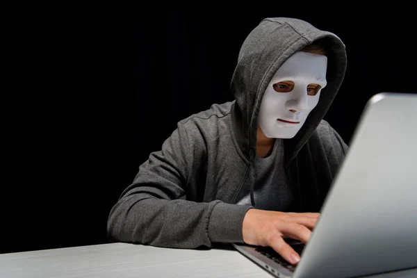 Troll internet anonyme en masque tapant sur clavier d'ordinateur portable isolé sur noir — Photo de stock