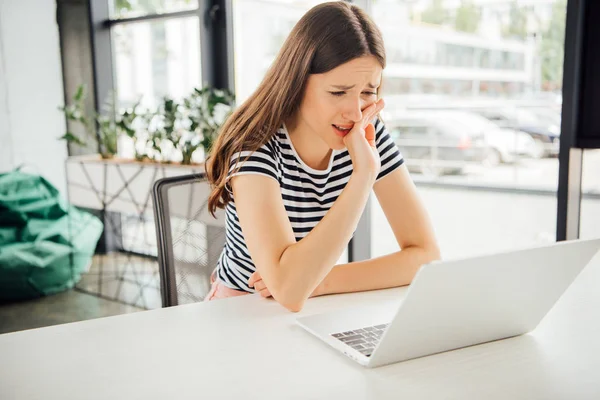 Menina triste em t-shirt listrada usando laptop em casa — Fotografia de Stock