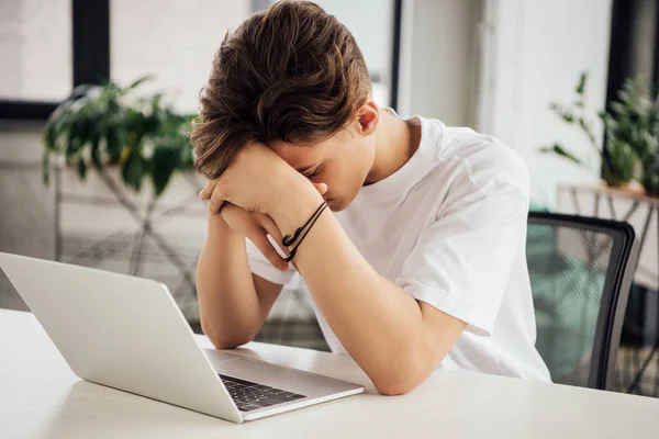 Triste adolescente menino em branco t-shirt usando laptop em casa — Fotografia de Stock