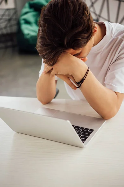 Triste adolescente menino em branco t-shirt usando laptop em casa — Fotografia de Stock