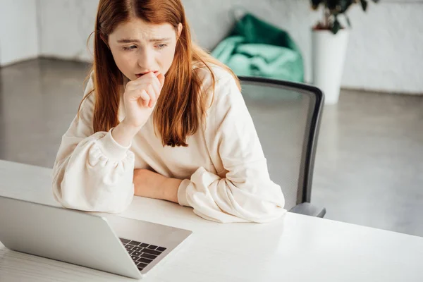 Sad teen girl sitting at table with laptop at home — Stock Photo