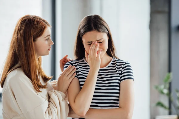 Teen girl supporting sad crying friend in striped t-shirt — Stock Photo