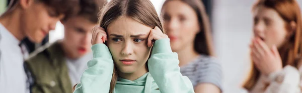 Panoramic shot of sad outsider girl standing in front of group of people — Stock Photo