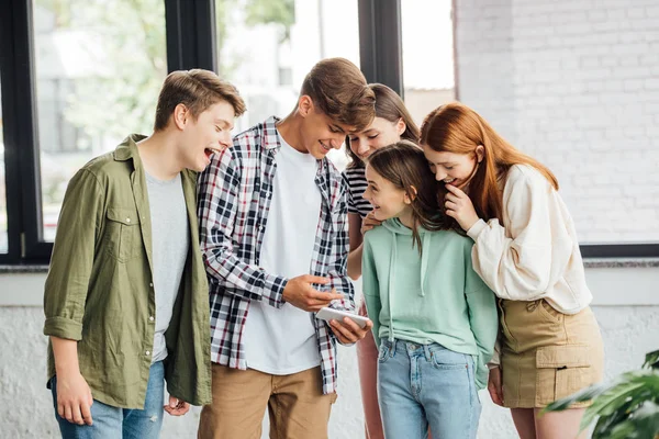 Group of happy friends laughing while using smartphone — Stock Photo
