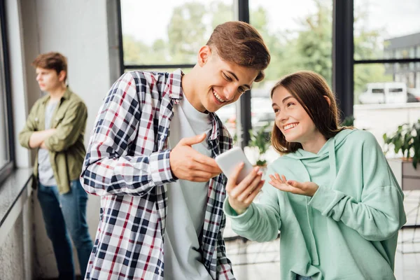 Two happy friends smiling while using smartphone in school — Stock Photo