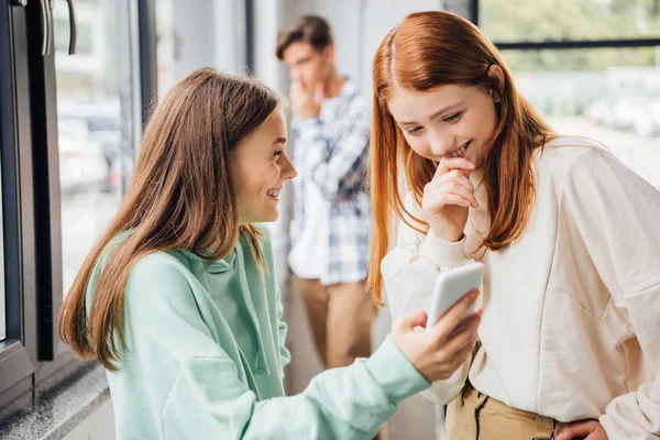 Два друга улыбаются во время использования смартфона в школе — стоковое фото