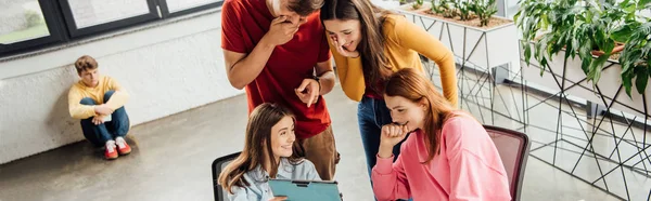 Tiro panorâmico de grupo de crianças em idade escolar sorrindo usando tablet digital em sala de aula — Fotografia de Stock