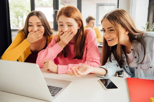 Drei aufgeregt lächelnde Mädchen, die in der Schule auf den Laptop-Bildschirm schauen — Stockfoto