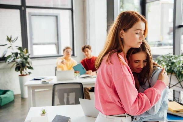 Chica de apoyo y abrazo triste amigo en la escuela - foto de stock