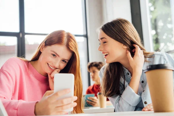 Zwei Mädchen lächeln und nutzen Smartphone in der Schule — Stockfoto