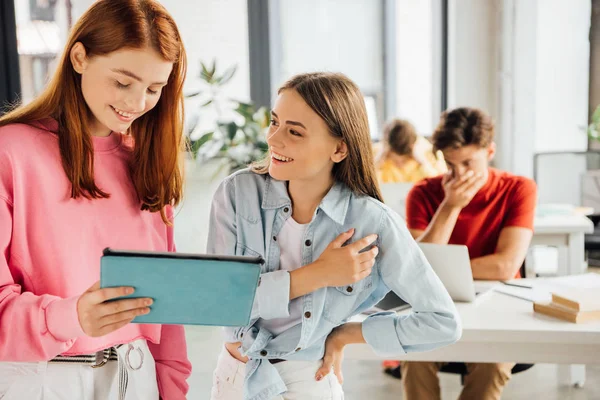 Escolares sonrientes que usan tabletas digitales y computadoras portátiles en la escuela — Stock Photo