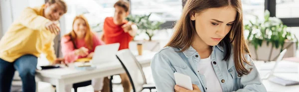 Panoramic shot of laughing schoolchildren bullying girl in school — Stock Photo