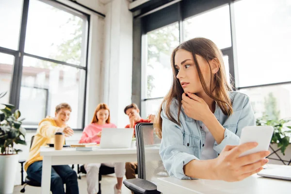 Risa colegiales intimidación triste chica con teléfono inteligente en la escuela - foto de stock