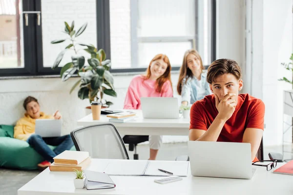 Escolares sentados en escritorios y usando computadoras portátiles en la escuela — Stock Photo