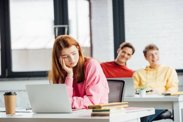 Sad pensive girl and classmates laughing at her in school — Stock Photo